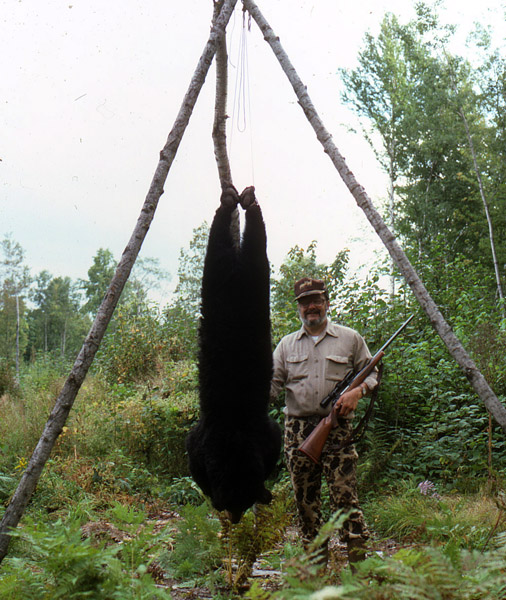 Dr Ken Nordberg with a black bear hanging from a tripod.